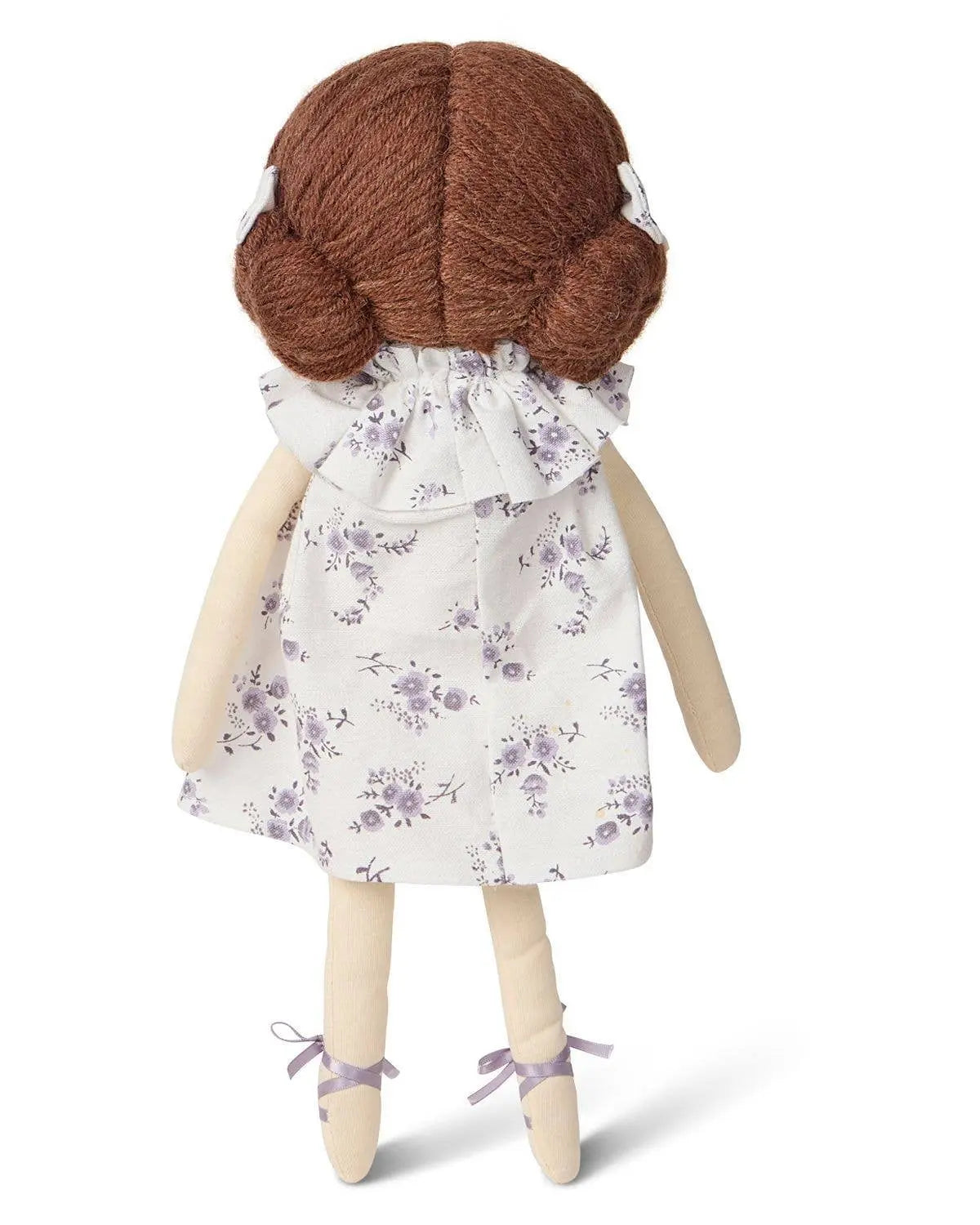 Doll with brown hair and a white dress with purple floral pattern on a white background
