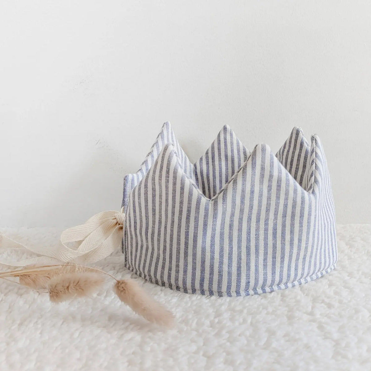 Blue striped natural linen dress-up crown with adjustable ties for children on a soft cream background