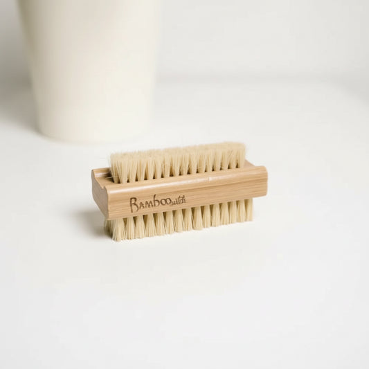 Bamboo and sisal nail brush on a white surface with a white cup in the background