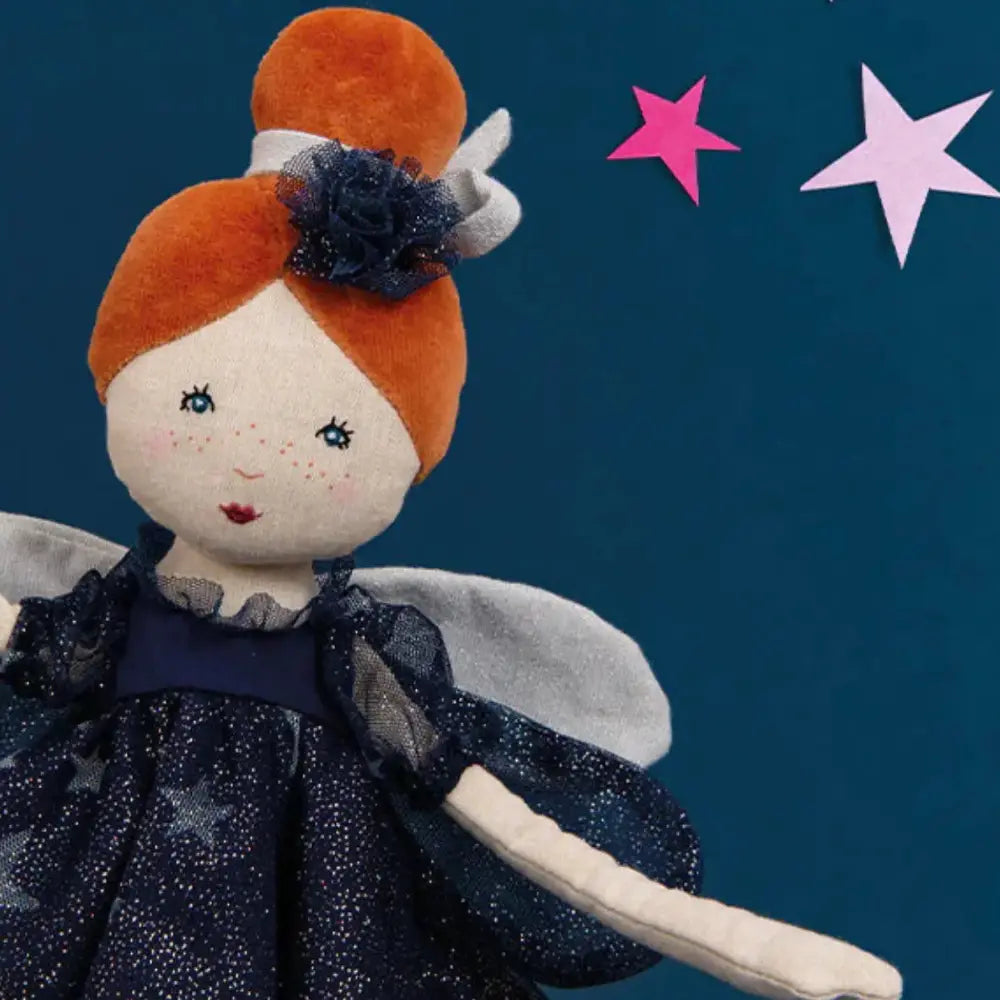 Fairy doll with orange hair and a dark blue dress against a dark blue background with pink stars.