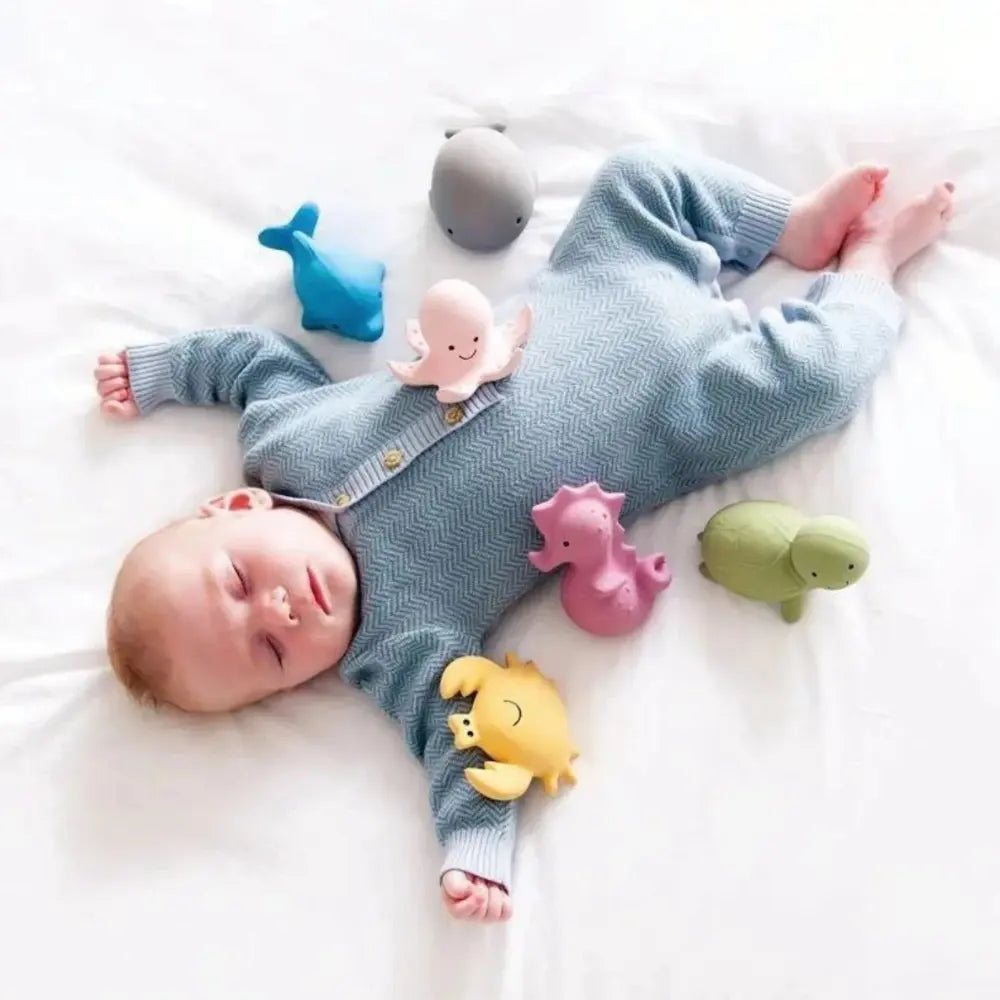 Baby sleeping next to natural rubber toys during sensory play and exploration
