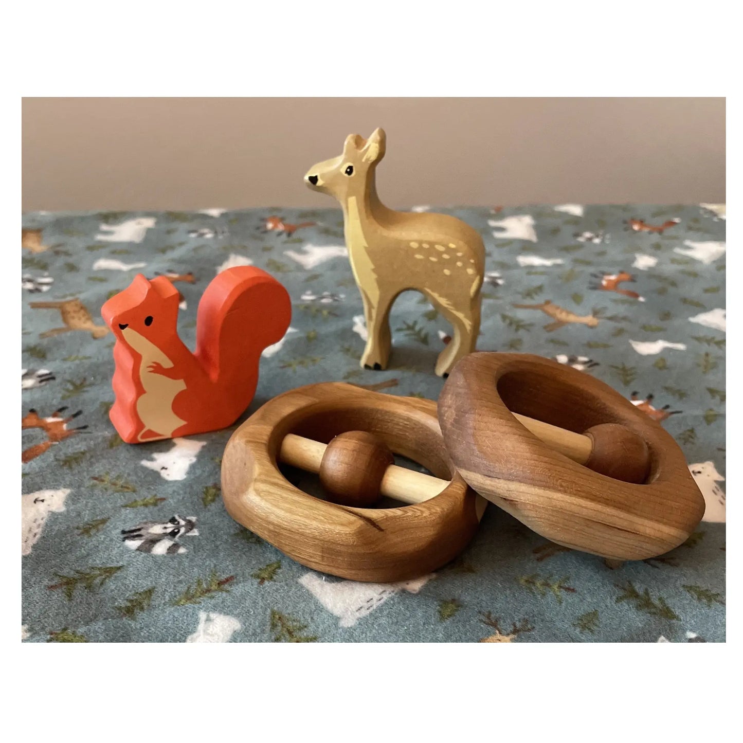 Natural wooden baby rattles displayed with woodland toys