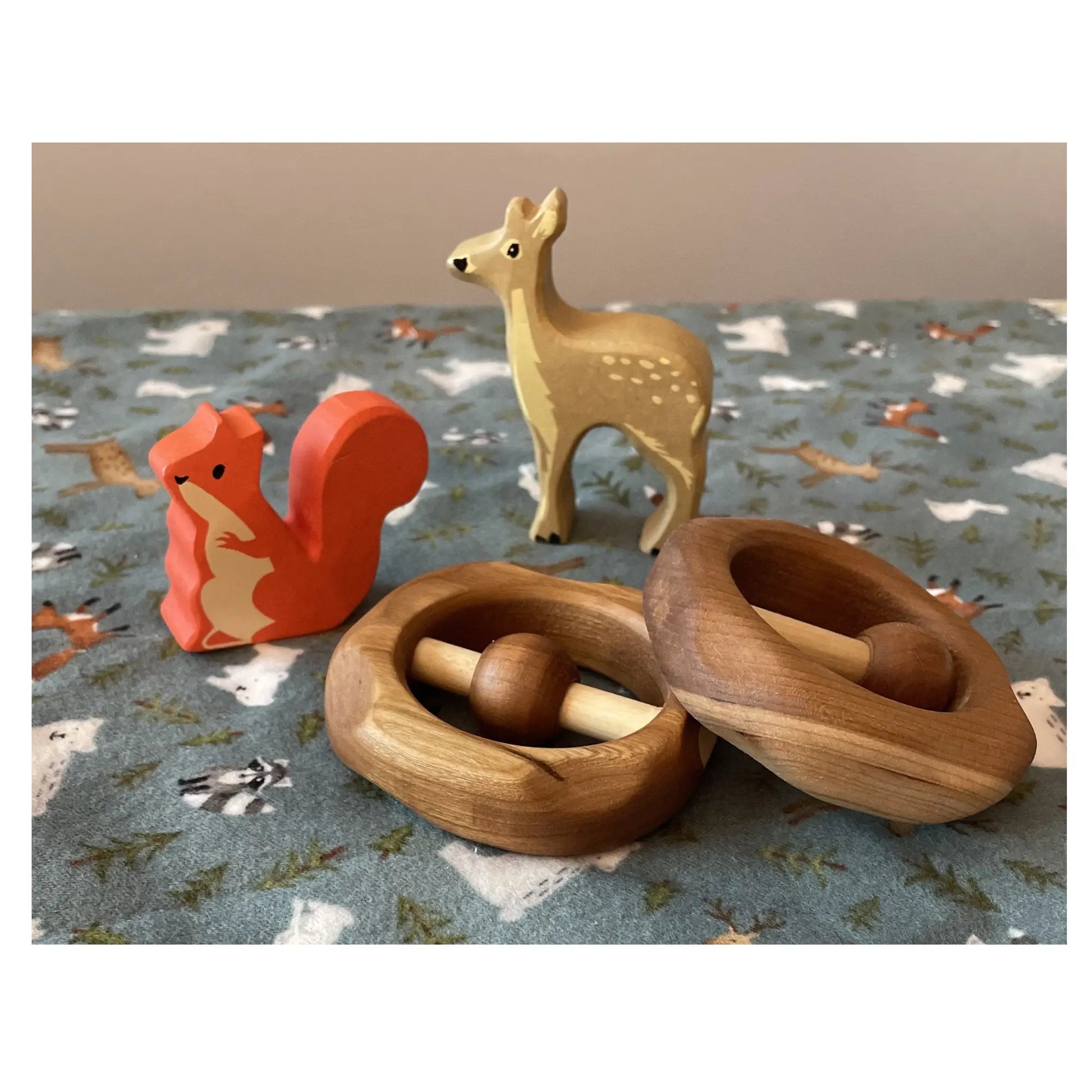 Natural wooden baby rattles displayed with woodland toys