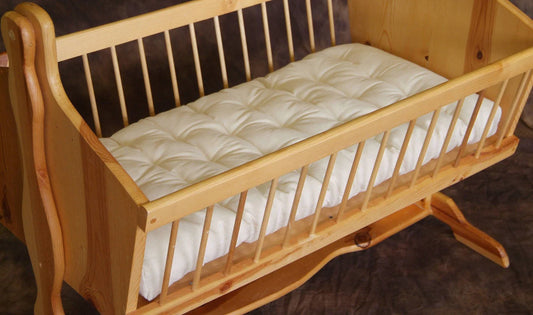  Natural Wool bassinet mattress inside a wooden bassinet