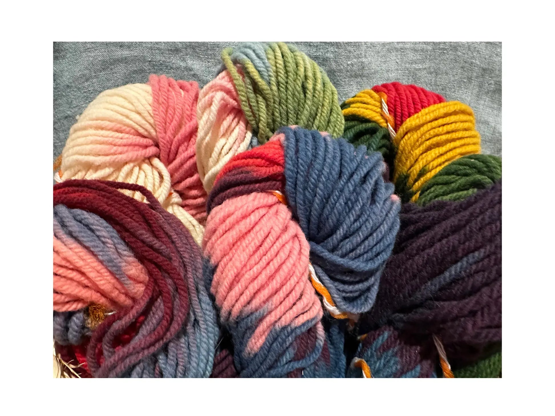 Colorful rainbow yarn balls on a textured surface