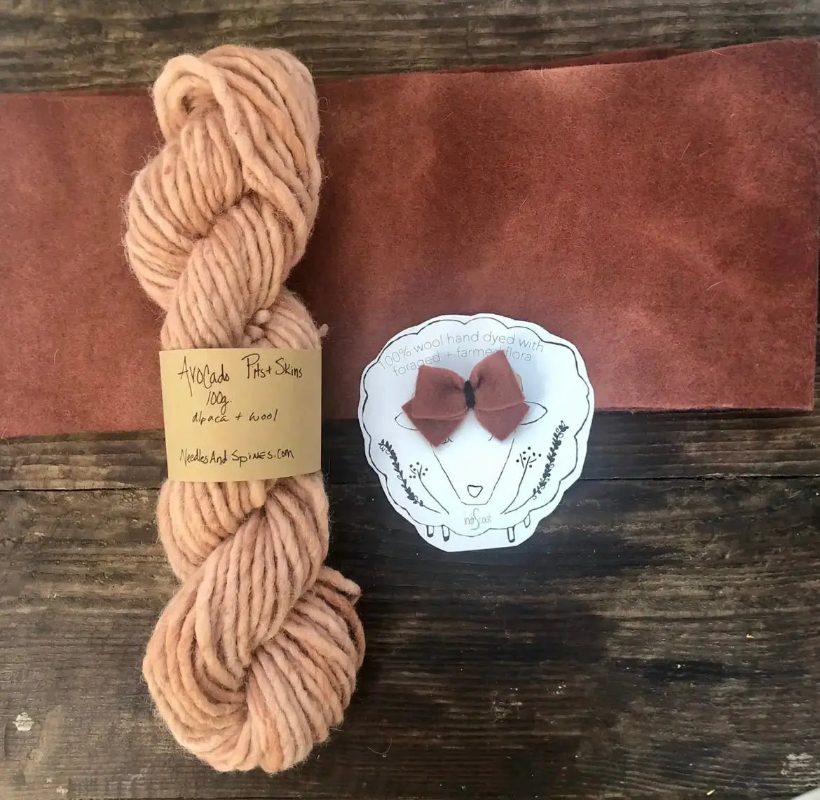 Peach skein of yarn with a label on a wooden surface, next to a small pink bow and white card.