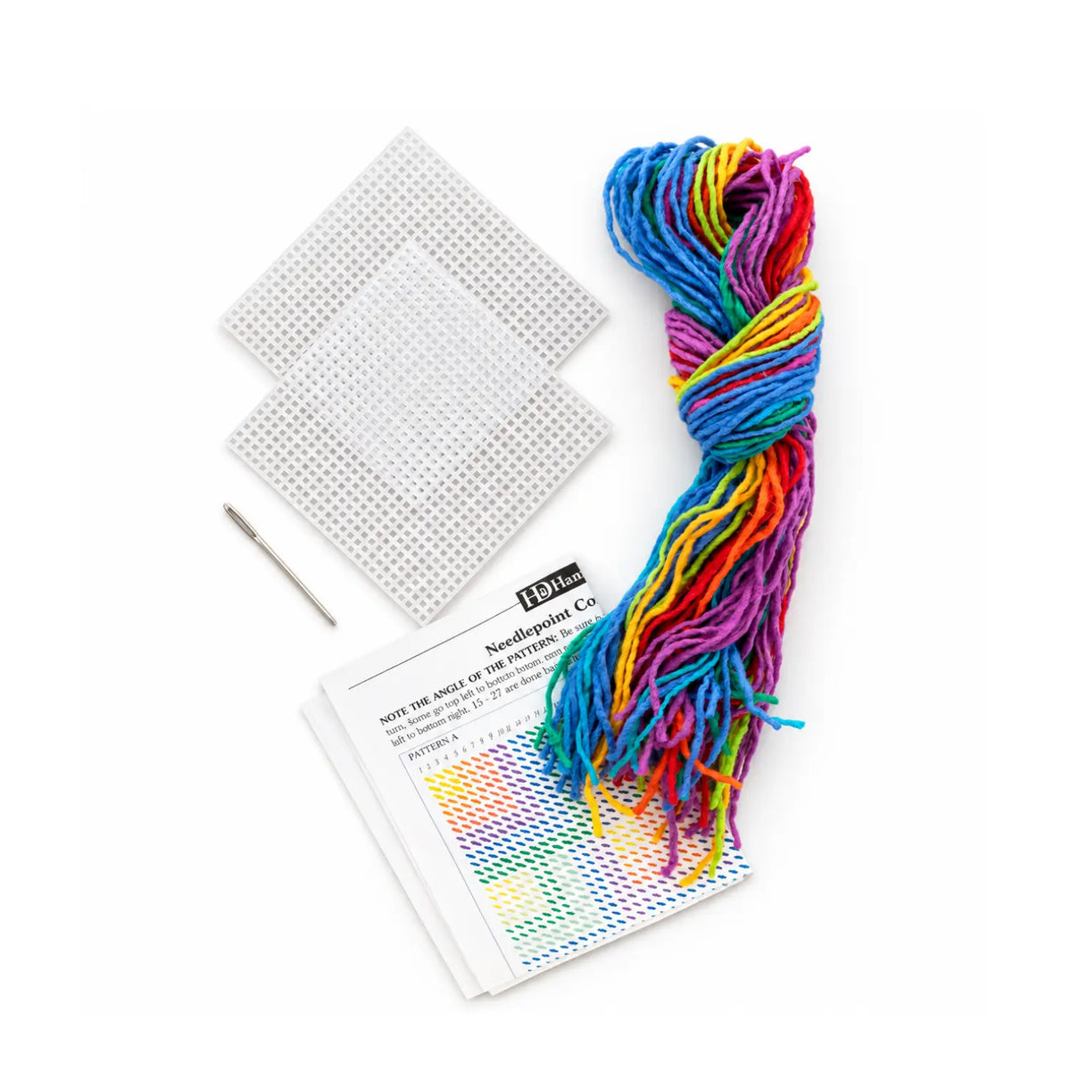 Needlepoint coaster kit contents: two 4-inch plastic canvases, a metal needle, rainbow wool yarn and pattern instructions