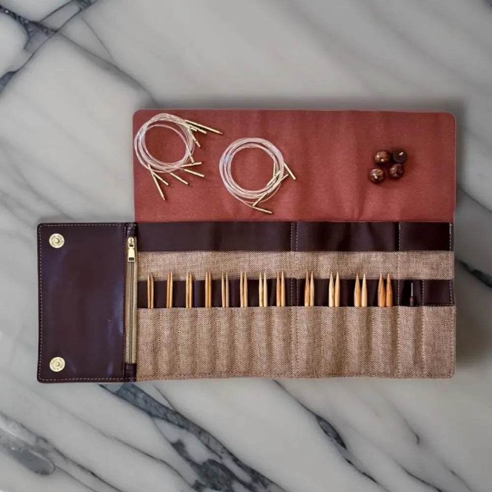 Knitting needle set in a brown case on a marble surface