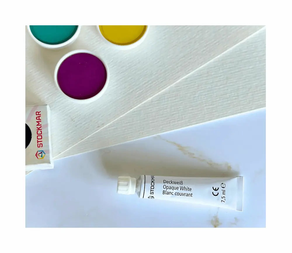 Opaque watercolor paint set detail showing opaque white, paint cakes on watercolor paper for layering and color mixing