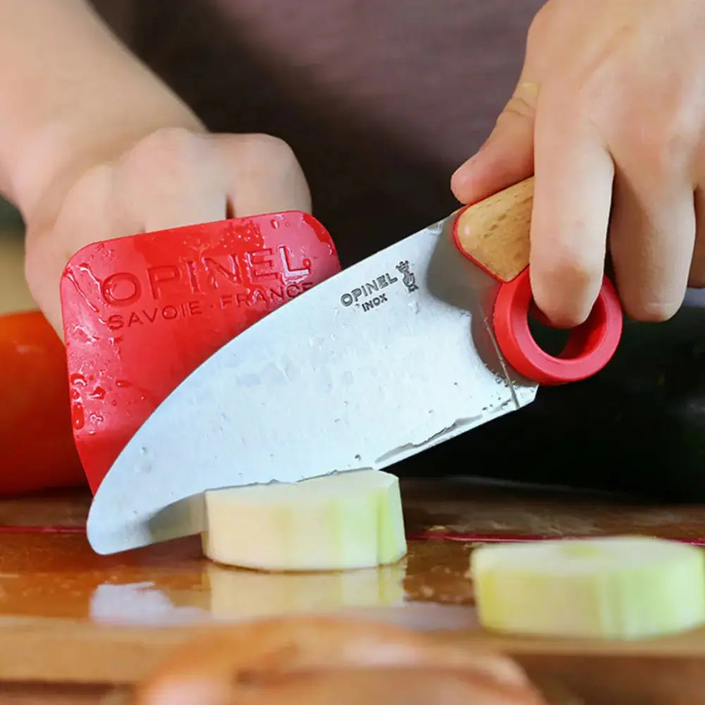 Opinel knife being used to slice an apple on a cutting board.