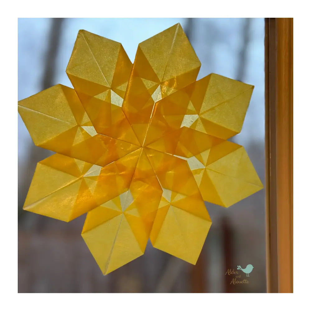 Close-up of layered orange and yellow kite paper window star showing translucent color blending