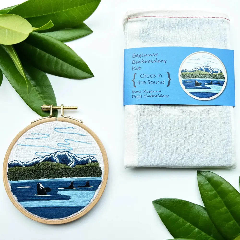 Finished orca embroidery project next to cotton project bag included in kit