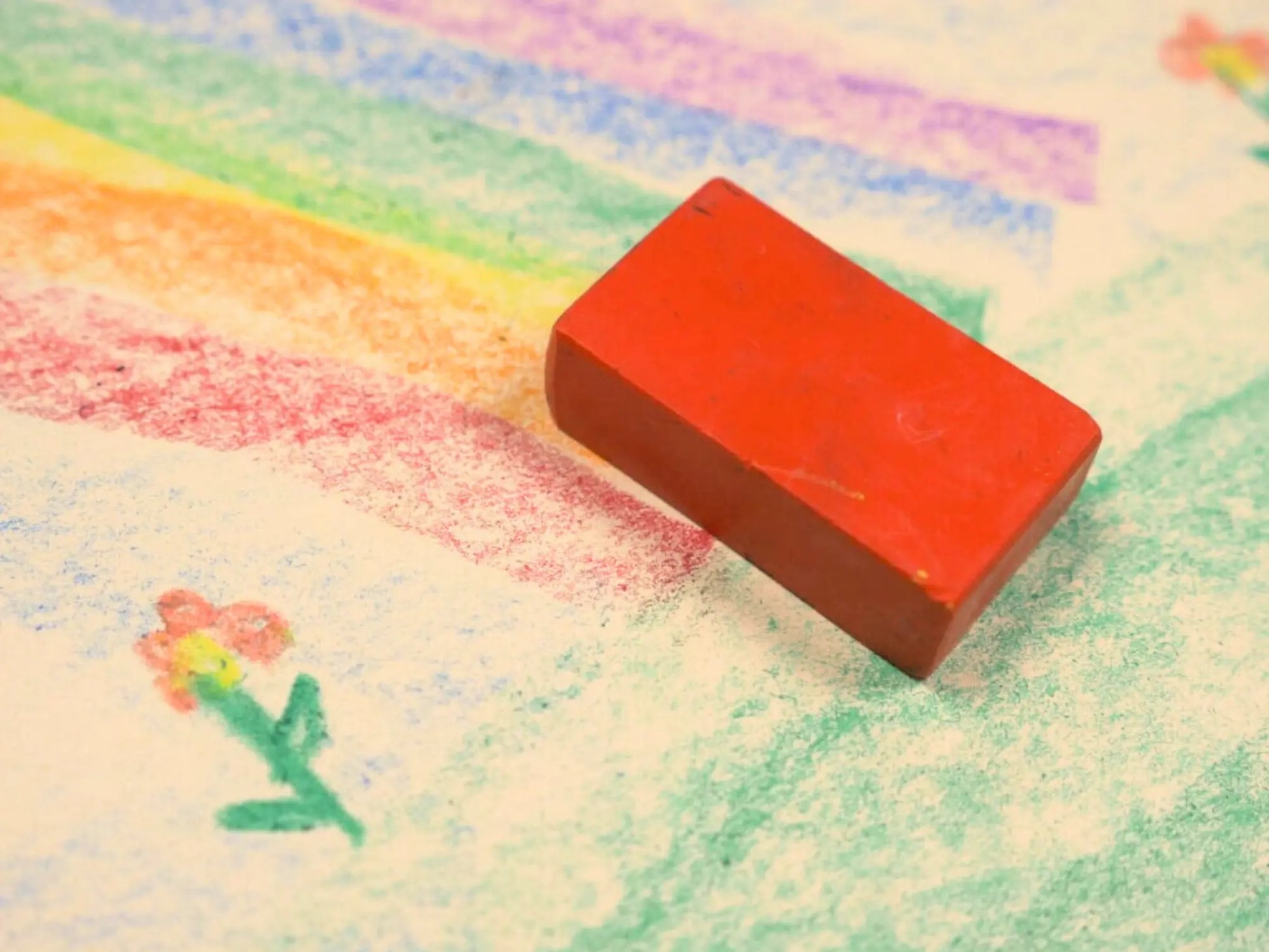 Red Filana block beeswax crayon on a piece of paper with colorful crayon drawings