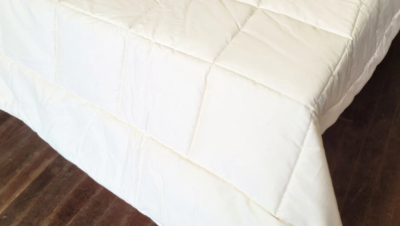 Close-up of quilted stitching on organic cotton comforter showing structured square pattern