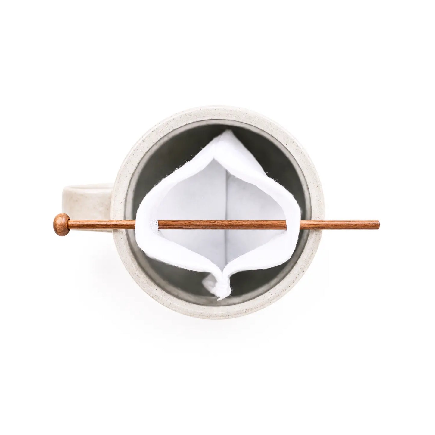 A top-down view of a white ceramic mug with a organic cotton tea bag held up by a balancing stick.