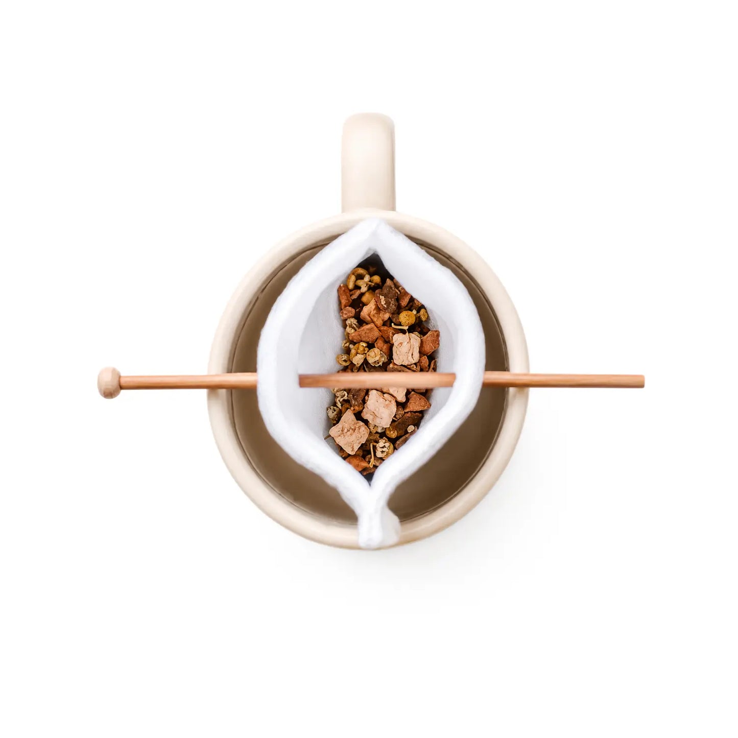 Top-down view of a beige ceramic mug with a organic cotton tea bag holding loose-leaf herbal tea