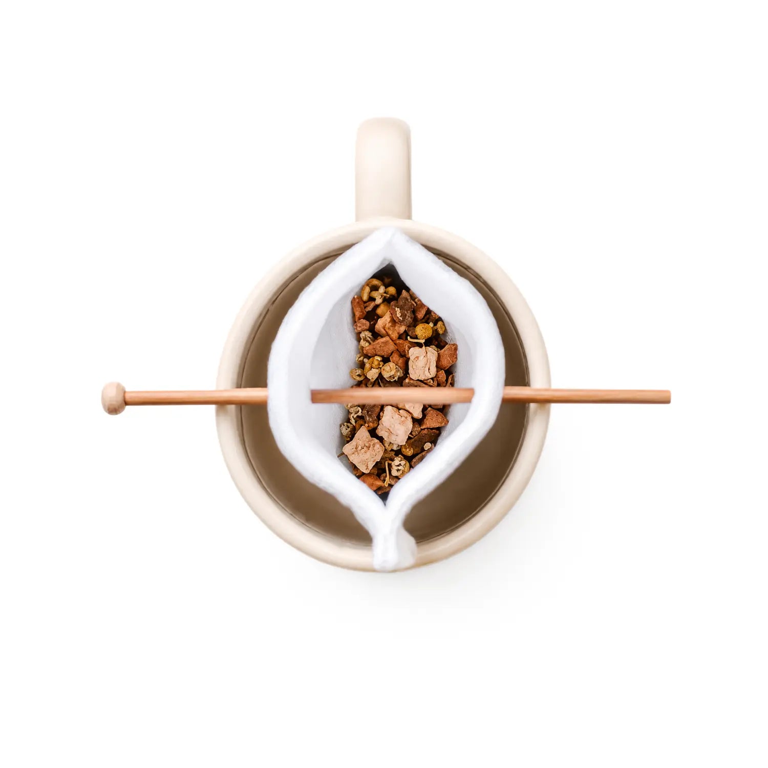 Top-down view of a beige ceramic mug with a organic cotton tea bag holding loose-leaf herbal tea