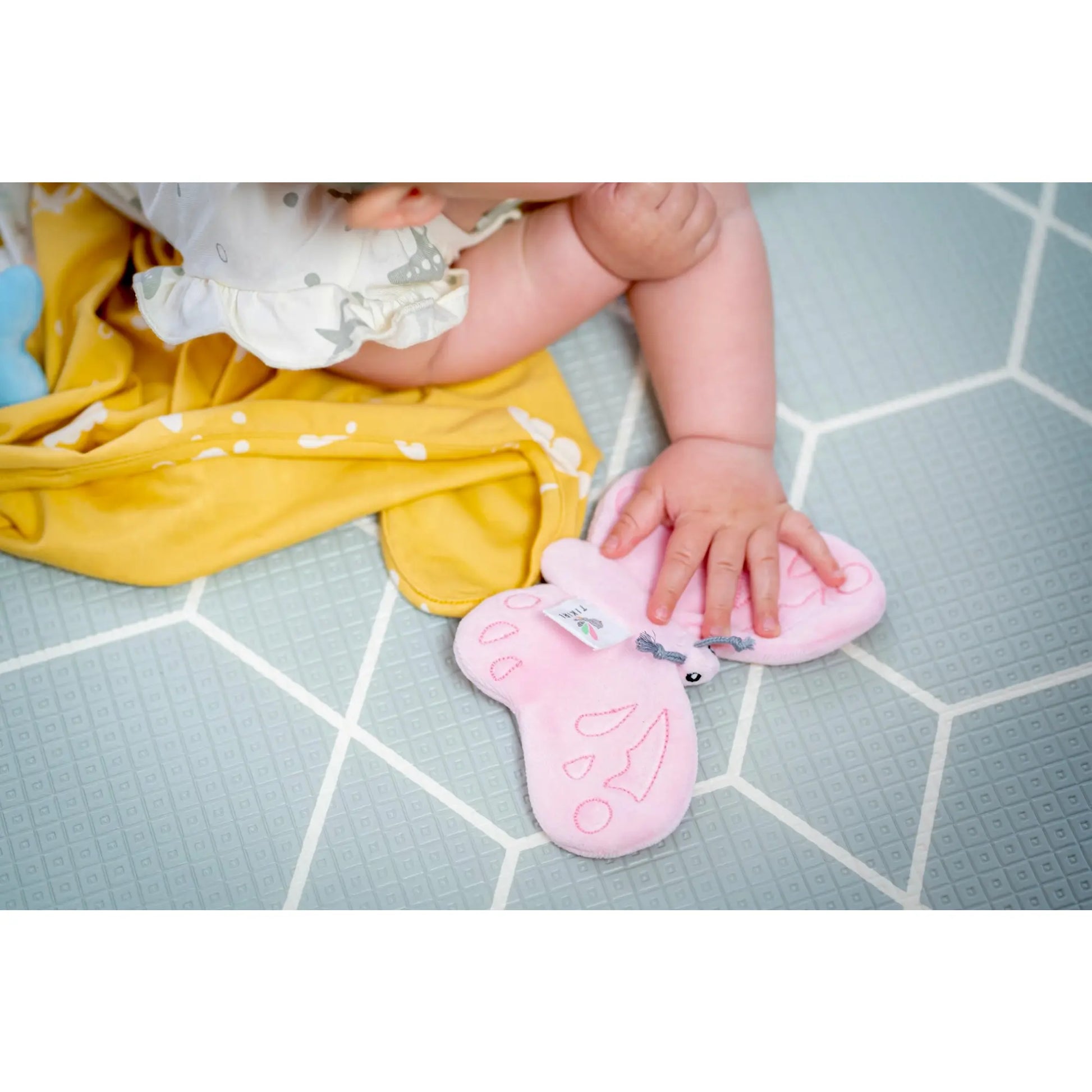 Infant playing on the floor with a pink butterfly crinkle toy