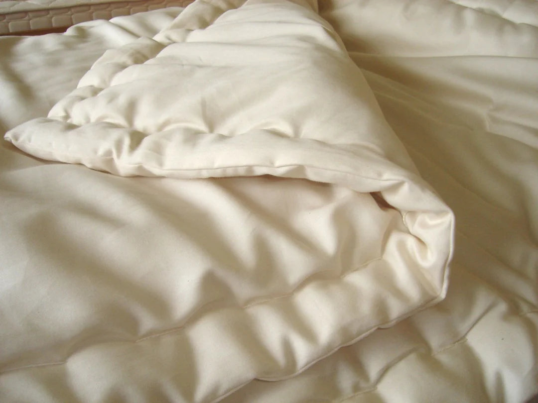 Organic wool comforter folded on bed showing quilted texture and soft drape