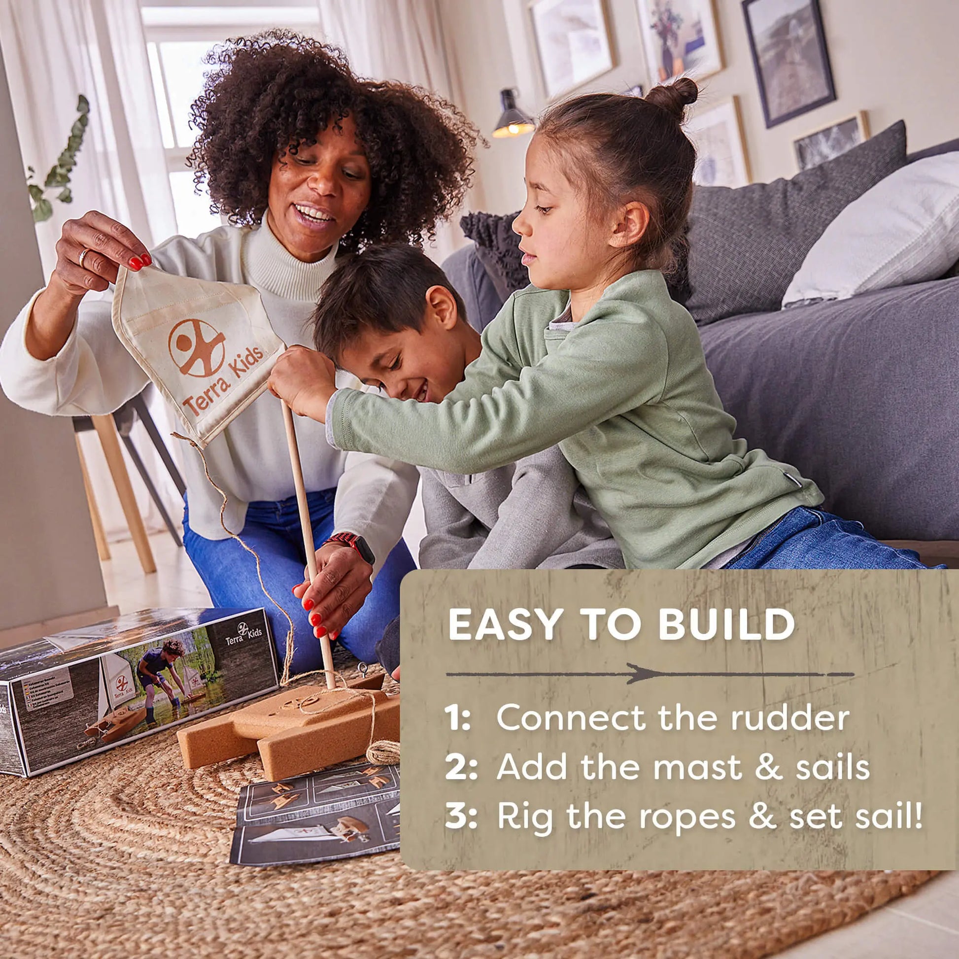 Woman and two children putting together a toy sailboat set in a living room.