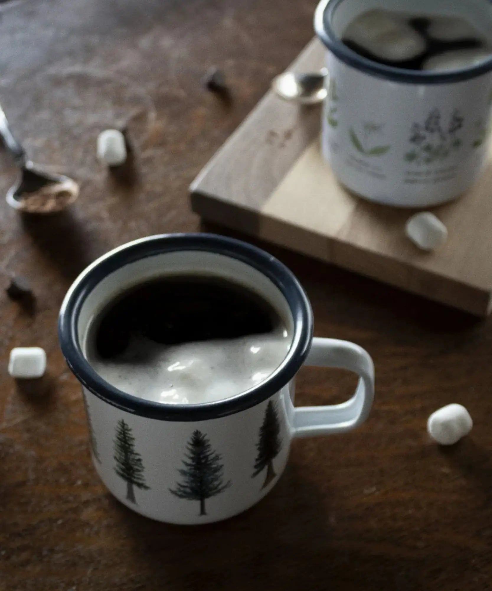 Mug with tree design filled with hot chocolate and marshmallows on a wooden surface
