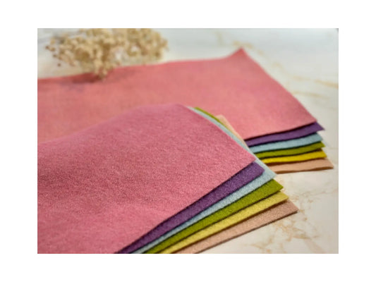 Pastel plant-dyed wool felt sheets layered to show soft color range and felt thickness