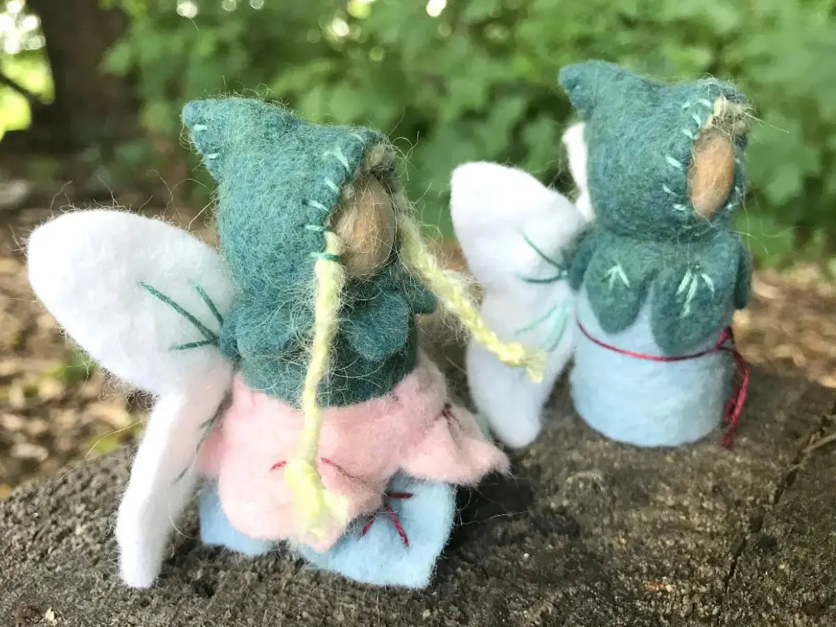 Two small fairy figurines made of wool fabric and peg dolls on a natural background