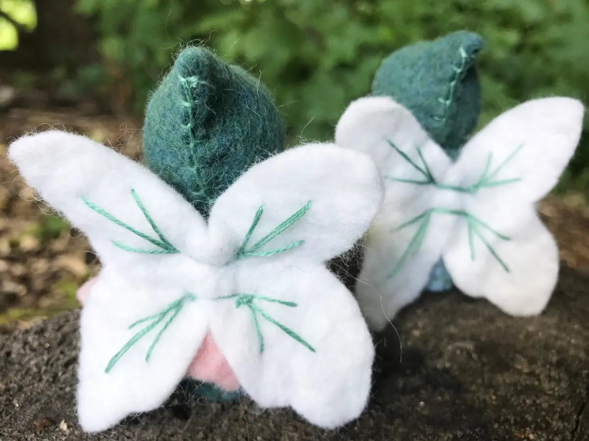 White fairy peg dolls with green accents on a natural background