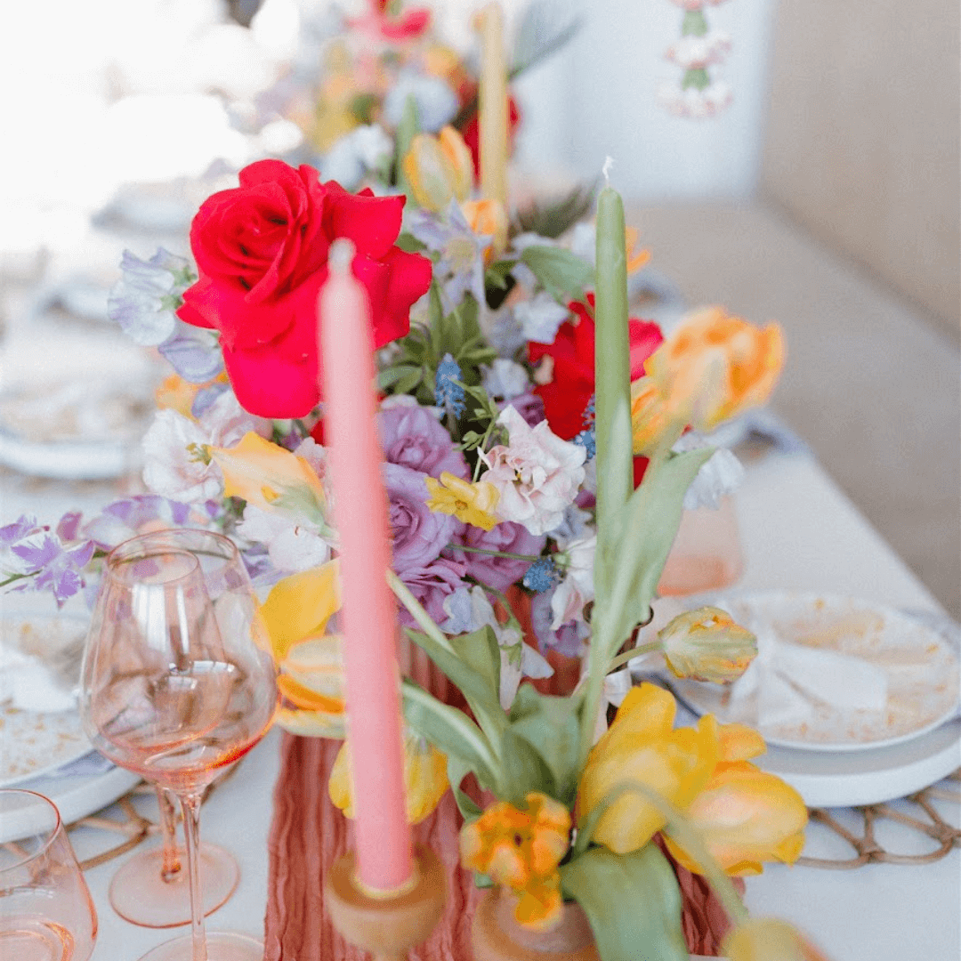 Colorful floral arrangement with candles on a table setting.