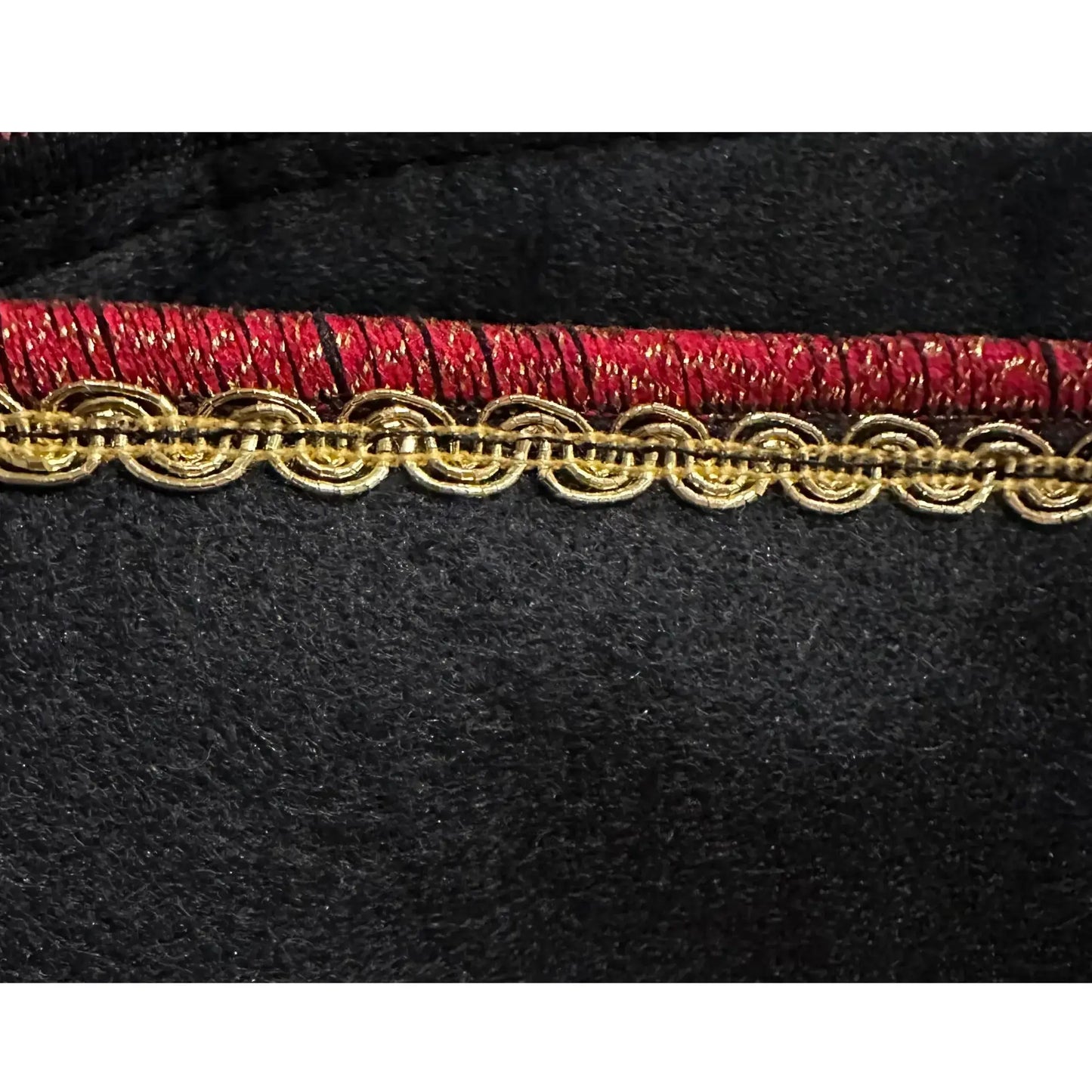 Close-up of red and gold decorative trim on black wool kids pirate hat 