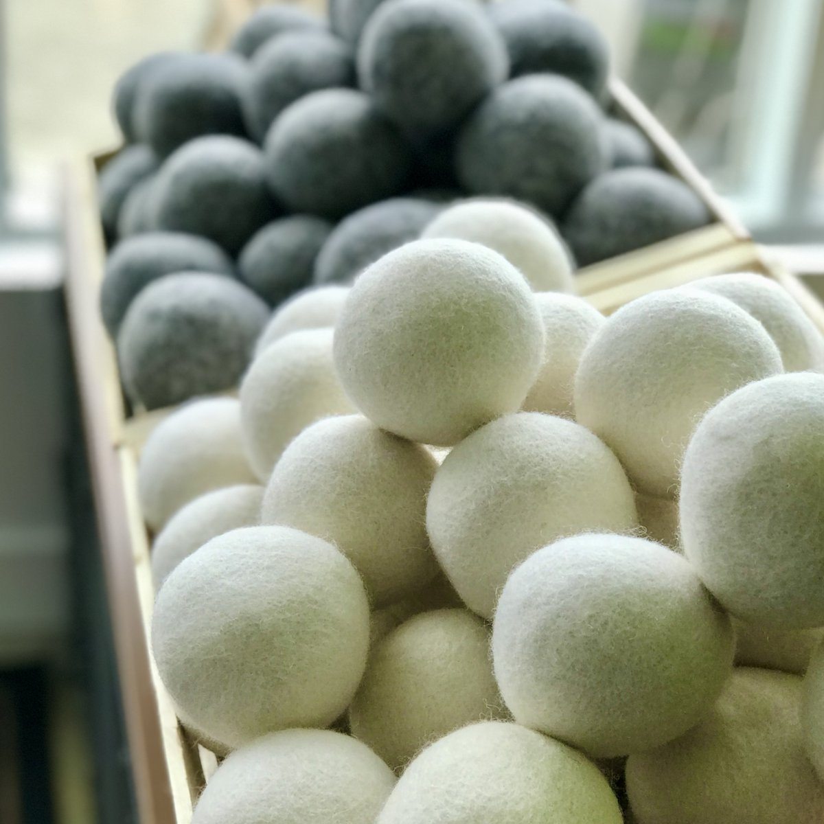 Close up of white and gray wool dryer balls in wooden boxes