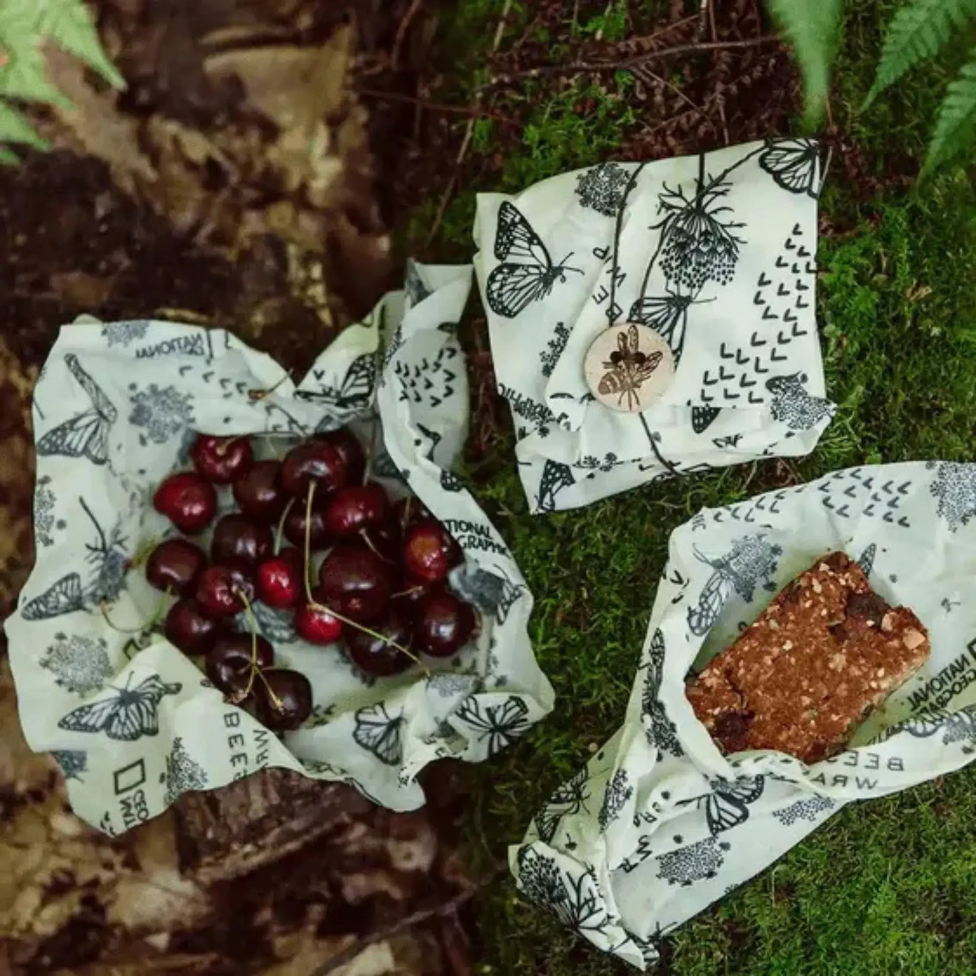 Cherries and a snack bar on patterned beeswax wraps on a natural background