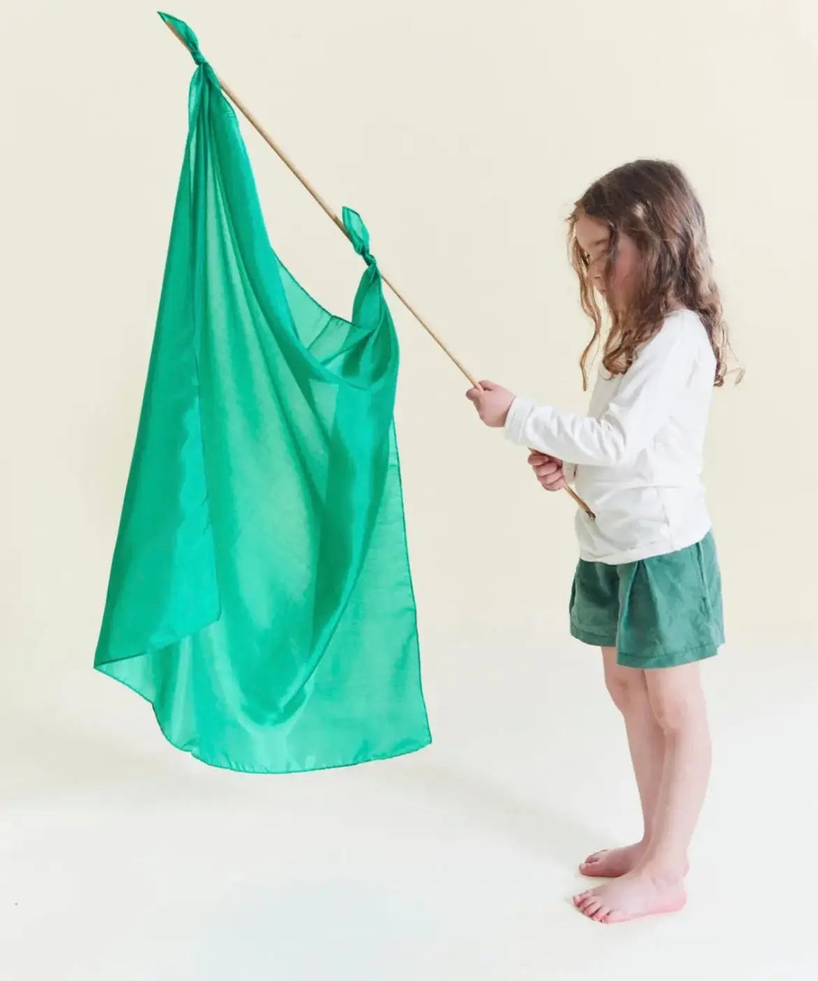 A child holding an Emerald Green Playsilk tied to a stick