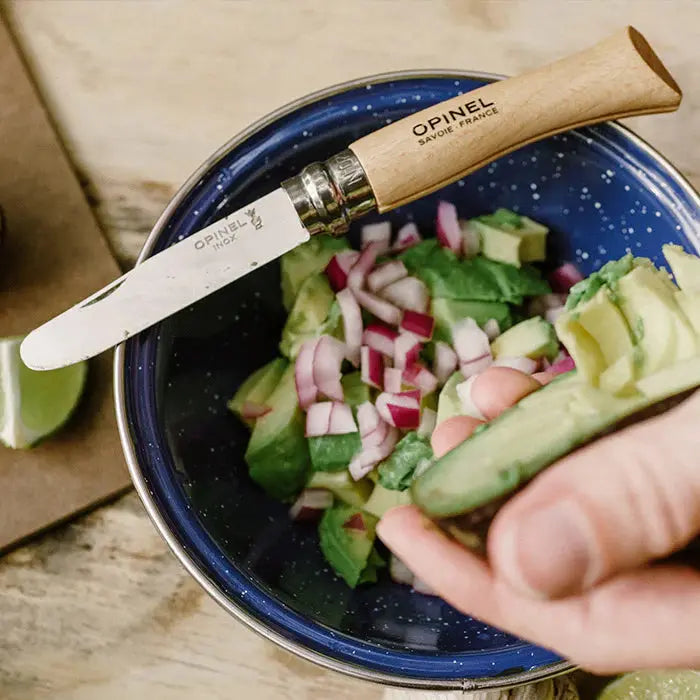 The Opinel No. 7 Junior Folding Pocket Knife  resting on the edge of a camp bowl of food