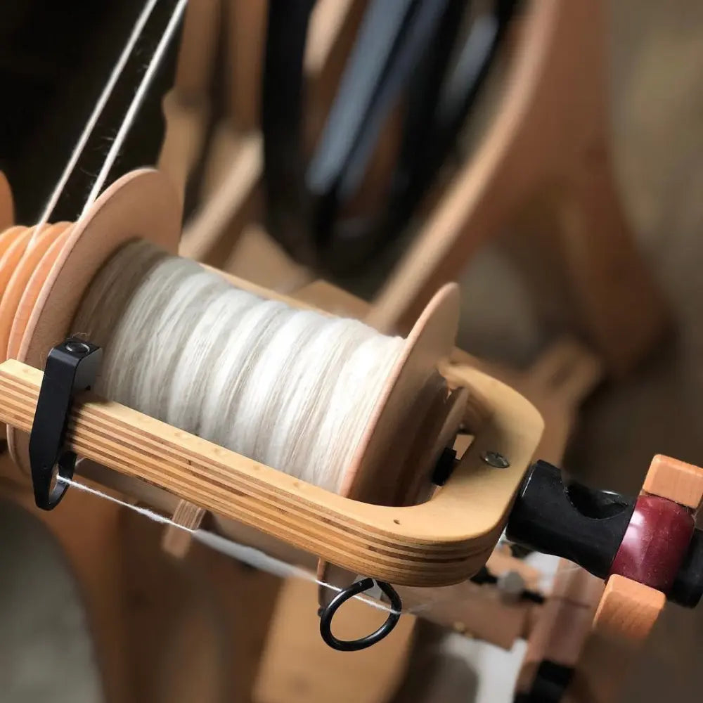 spinning undyed Polwarth wool combed top fiber on a spinning wheel
