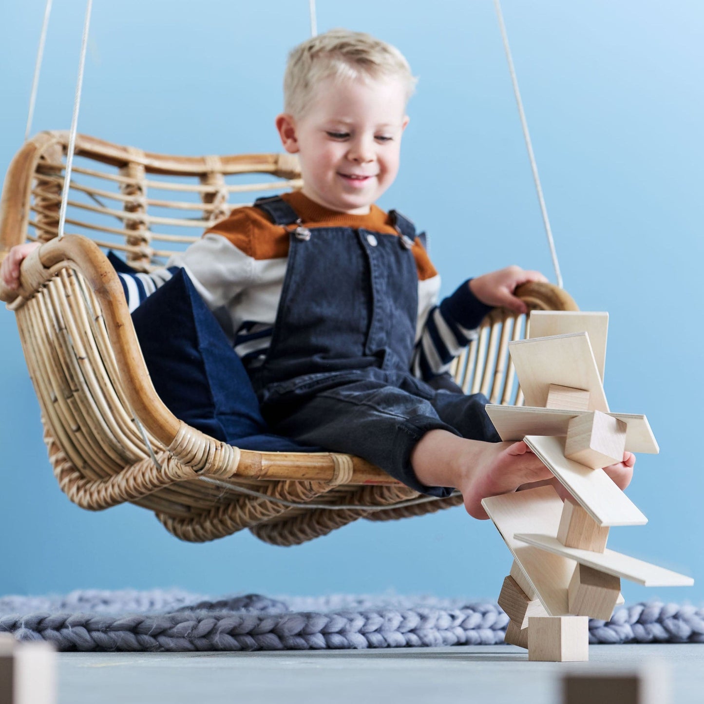 Preschool child building a tall structure with wooden blocks while seated