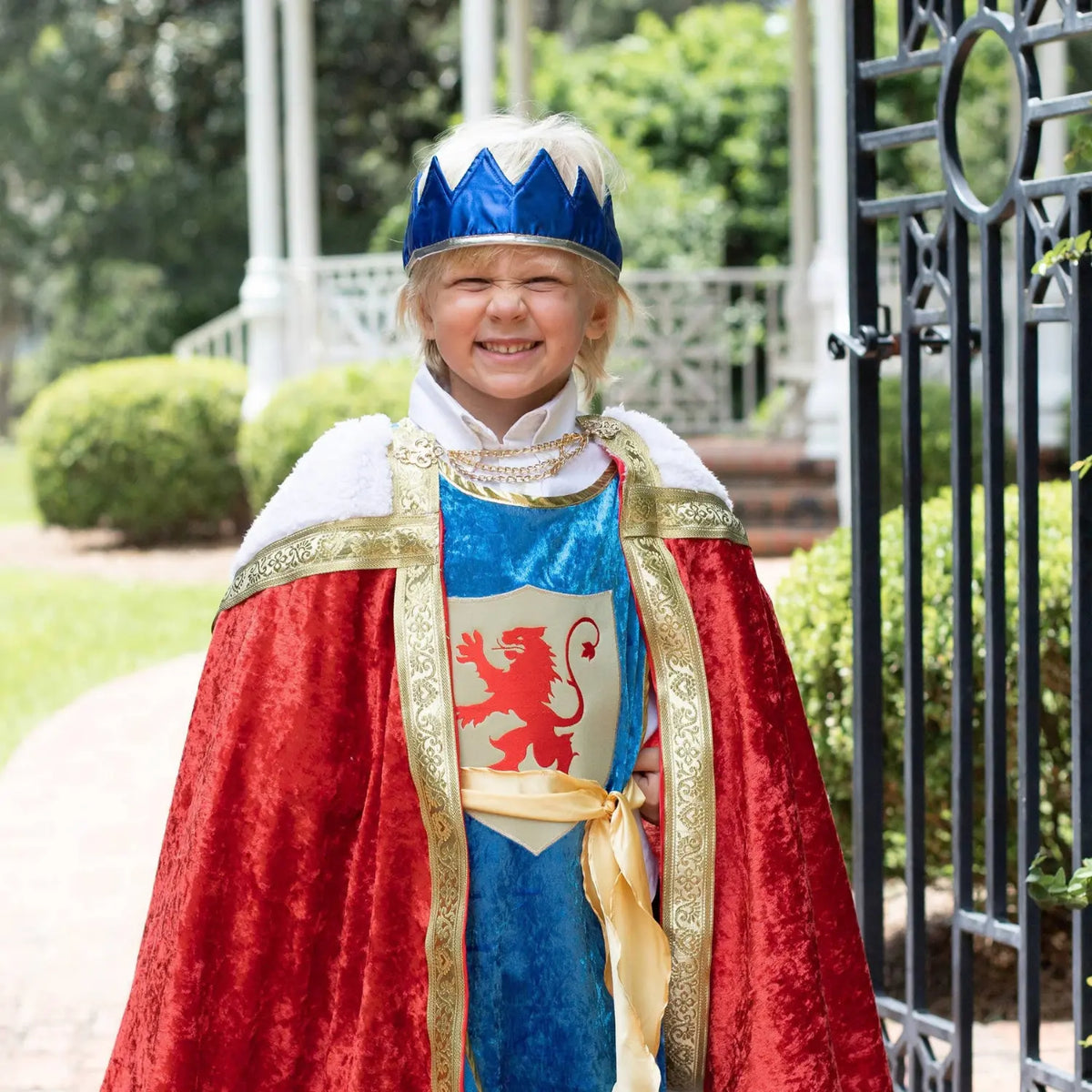 Child wearing a royal blue satin crown with a royal dress-up costume outdoors