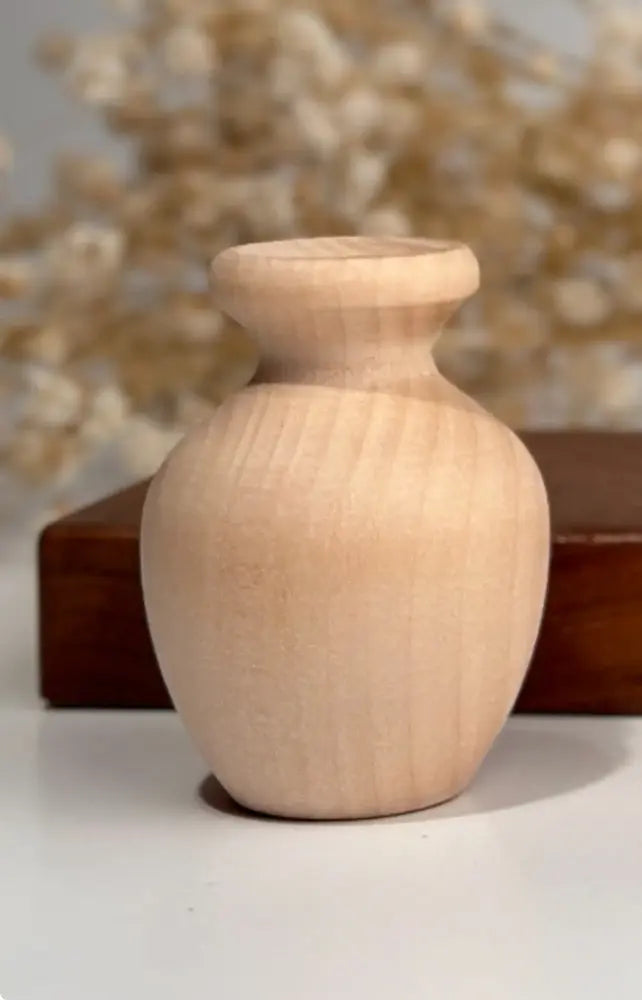 Wooden vase on a white surface with blurred decorative elements in the background