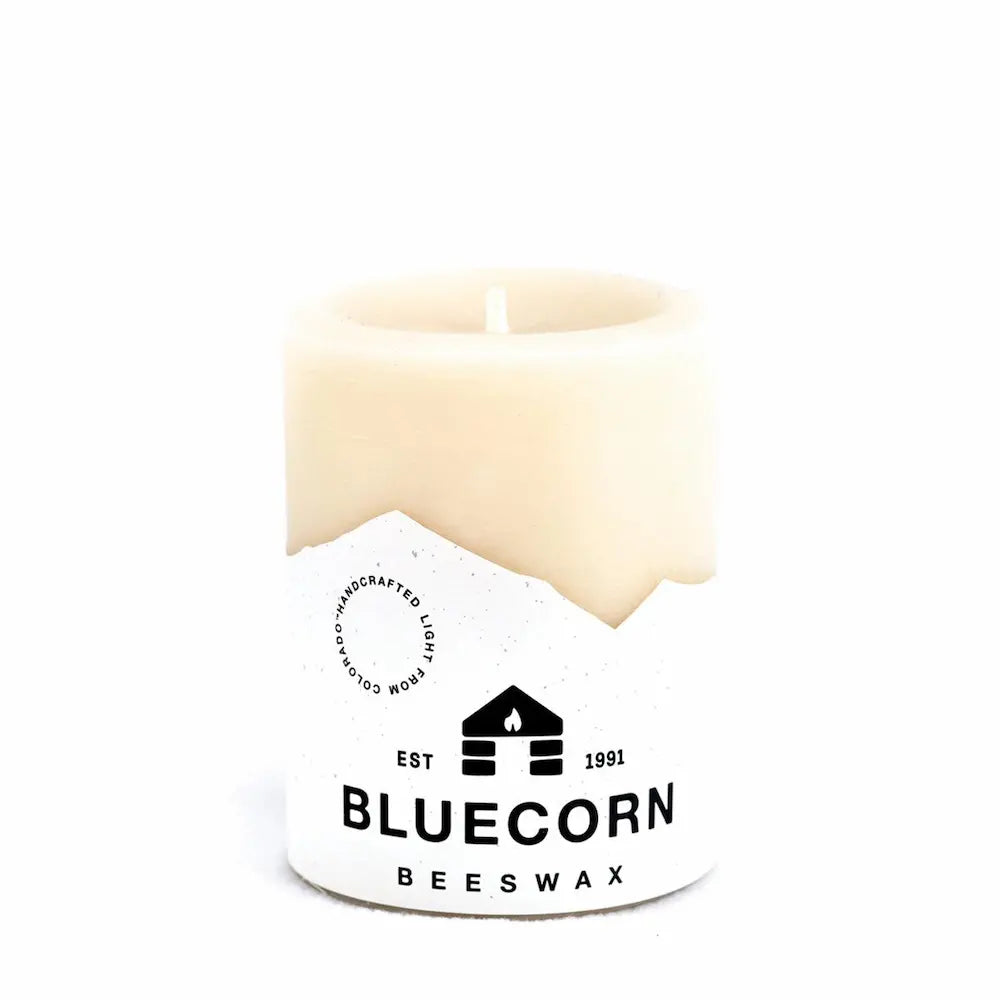 White candle with Bluecorn Beeswax logo on a white background