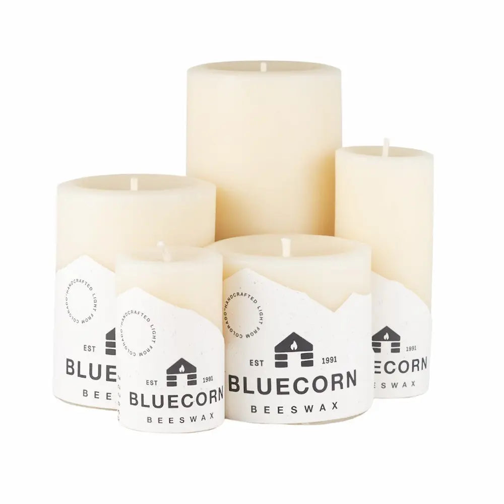 Set of four white candles with Bluecorn Beeswax labels on a white background