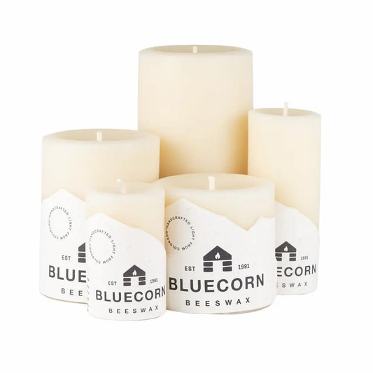 Set of four white candles with Bluecorn Beeswax labels on a white background