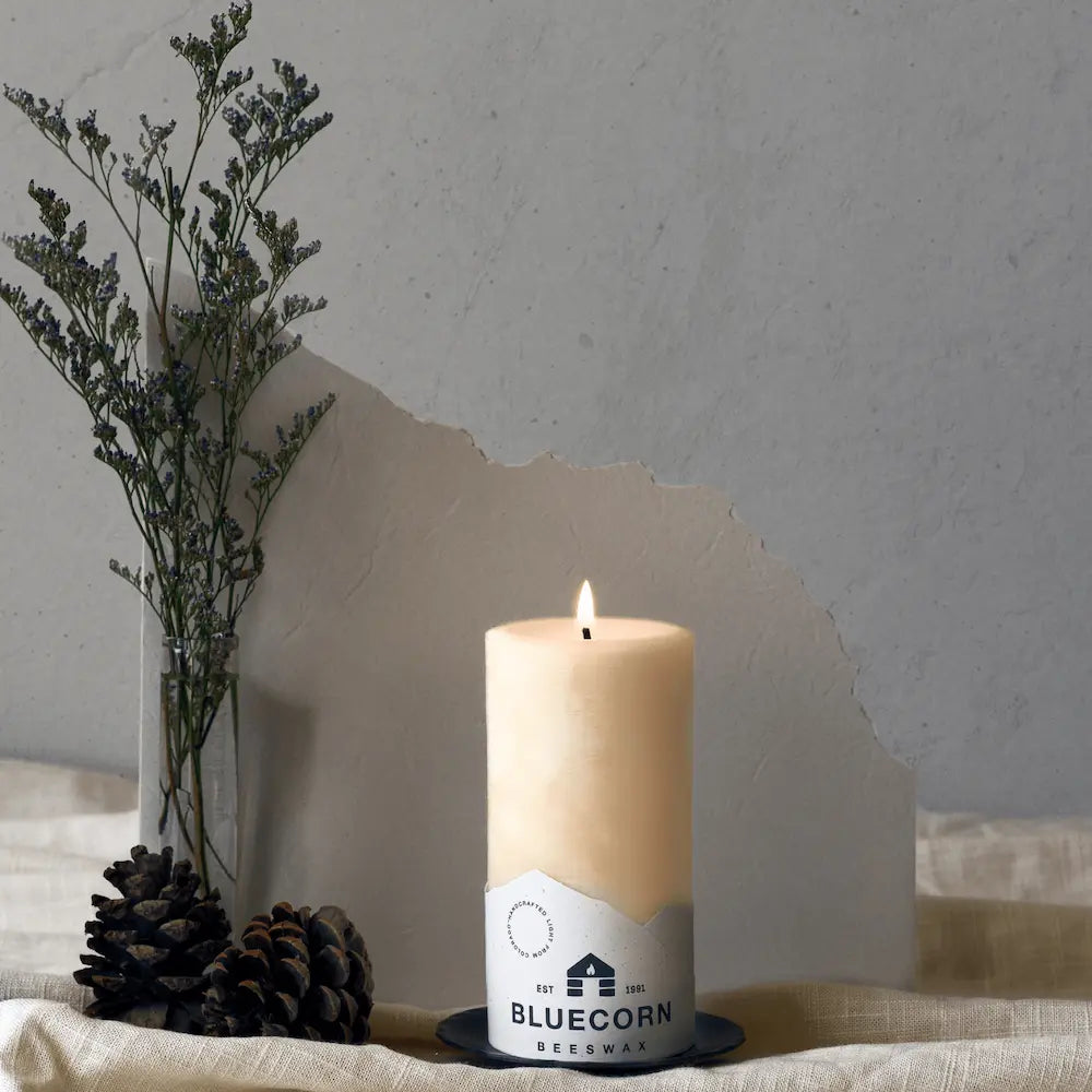 Candle with Bluecorn label on a surface with decorative elements