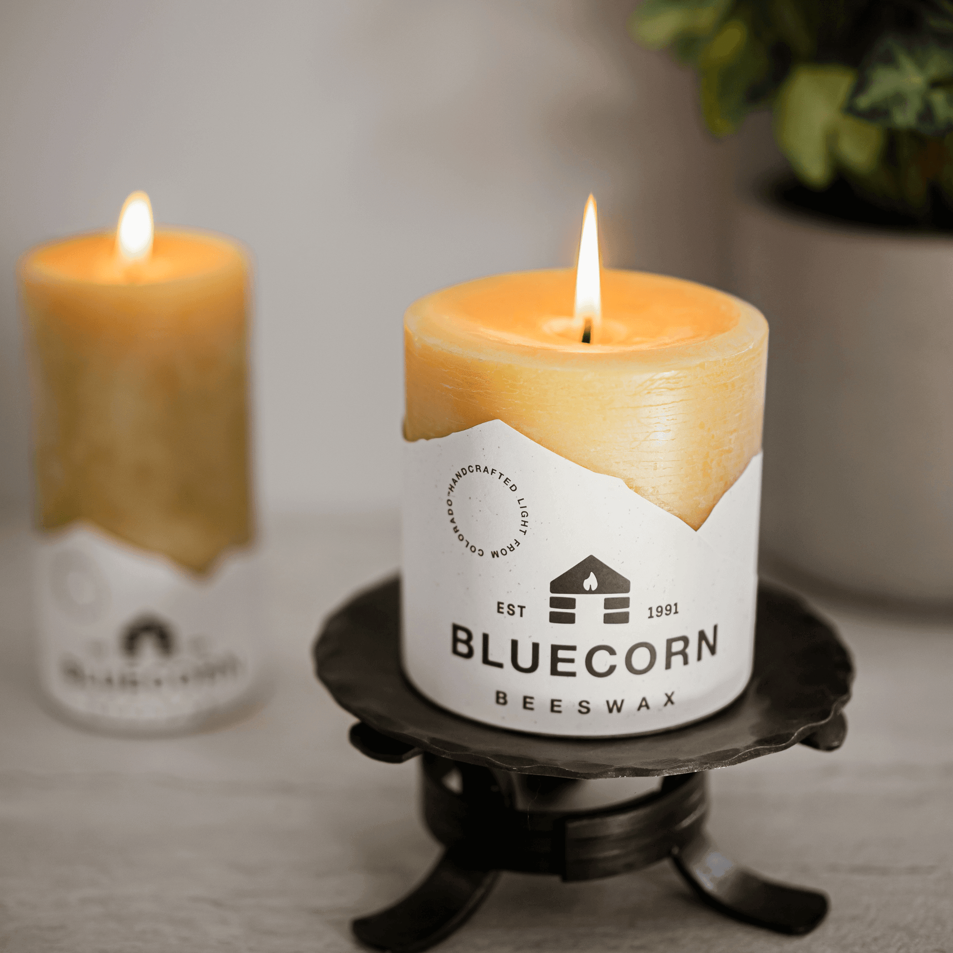 Bluecorn Beeswax candle on a stand with another candle in the background.