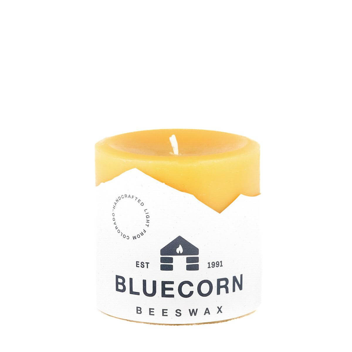 Yellow candle with a Bluecorn Beeswax label on a white background
