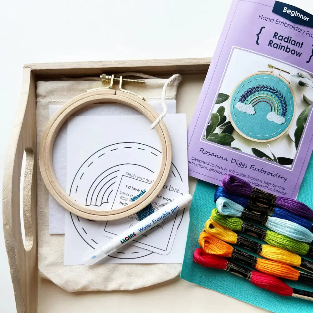 Beginner rainbow embroidery kit contents including embroidery hoop, thread, fabric, pattern, and instruction booklet