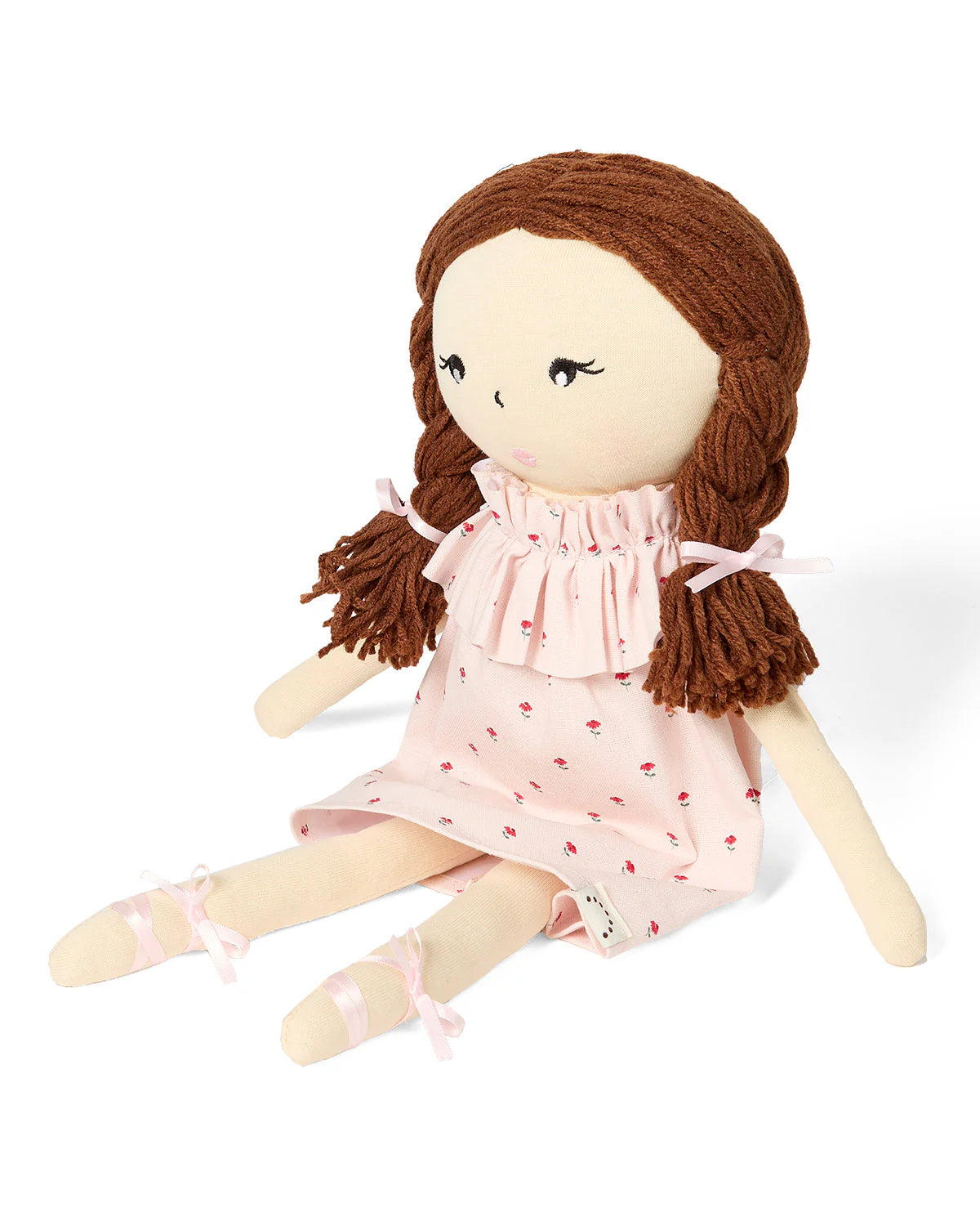 Stuffed doll with brown hair and a pink dress on a white background