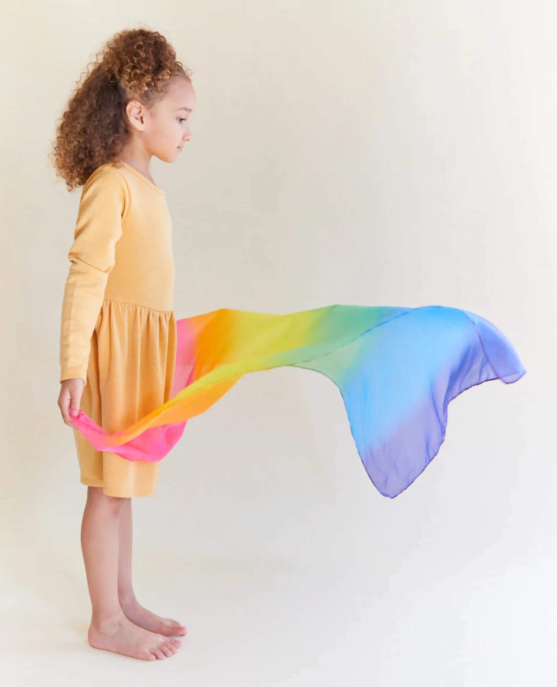 Girl waving an enchanted-rainbow-playsilk