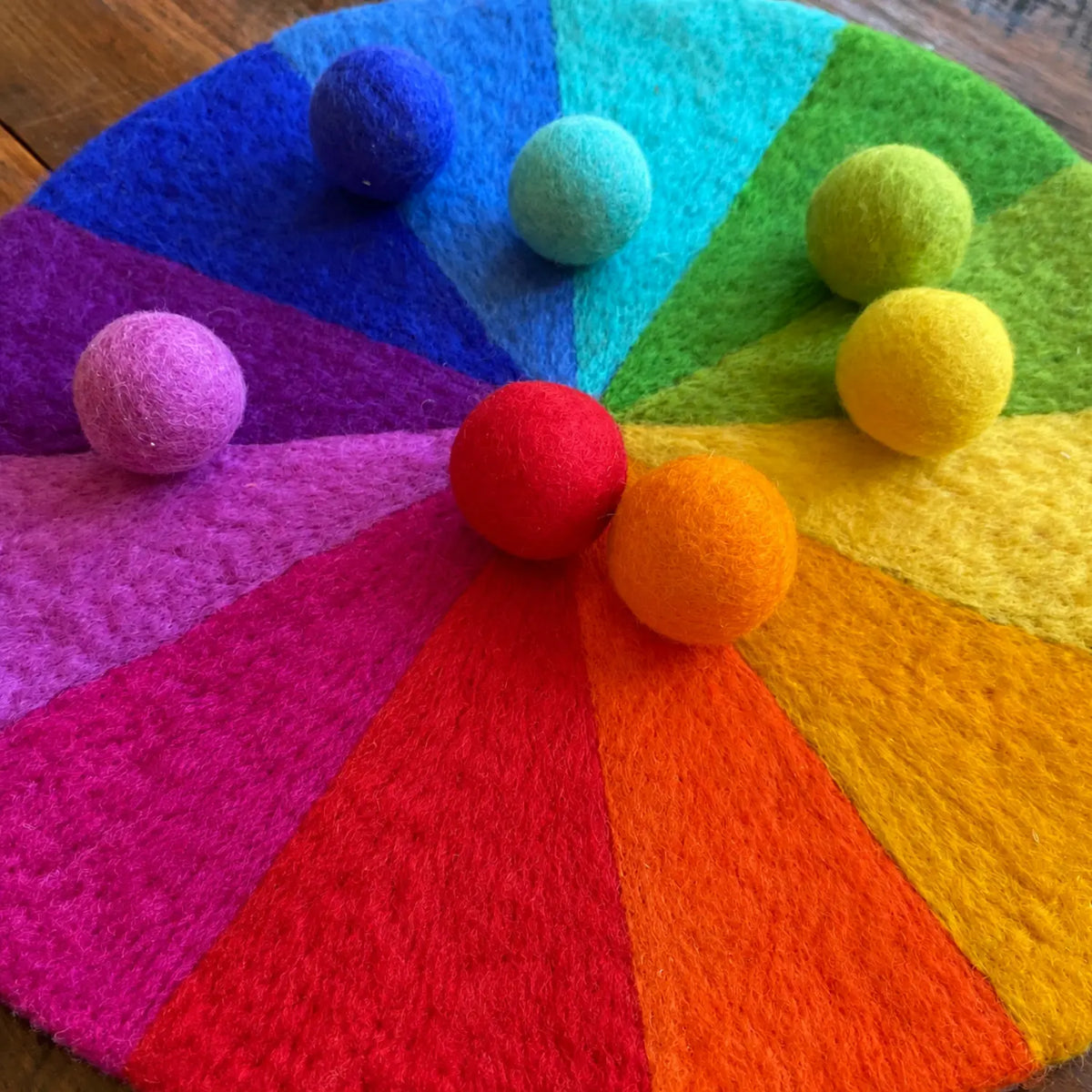 12-color rainbow felt play mat photographed at an angle on a wooden table