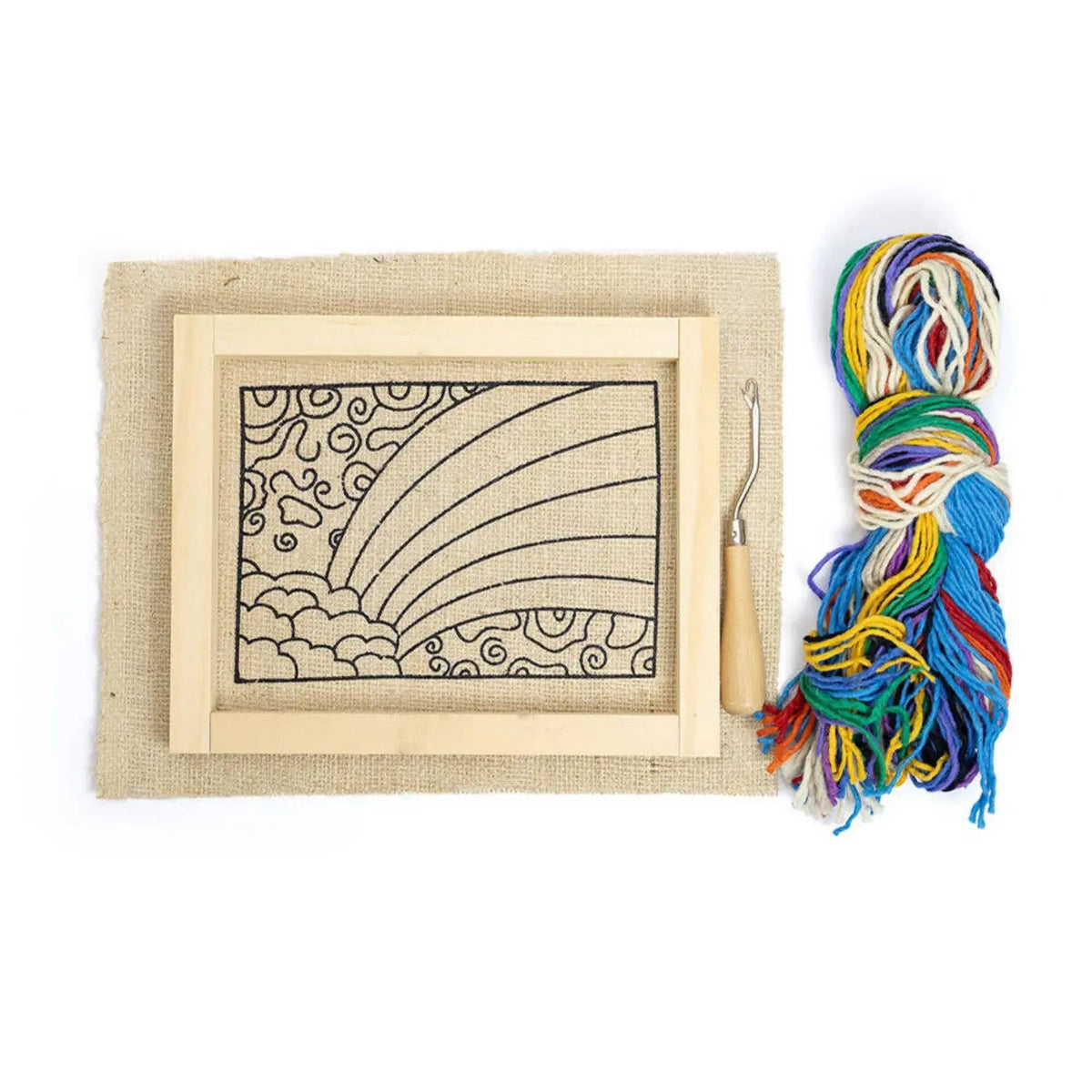Rug hooking kit contents: wooden frame with a printed rainbow pattern on burlap, wood-handled rug hook, and a bundle of rainbow wool yarn