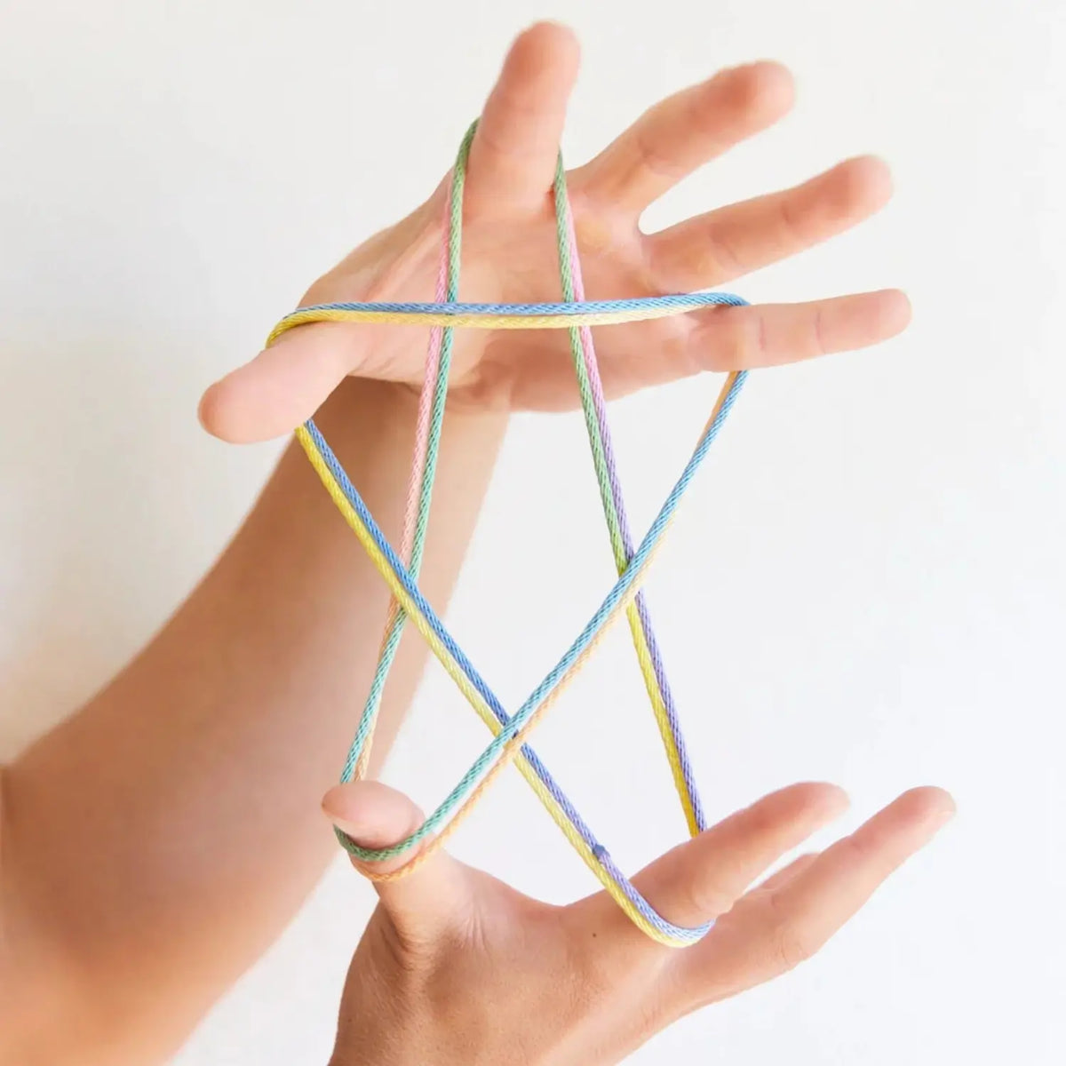 Star string figure made with rainbow string and held between two hands